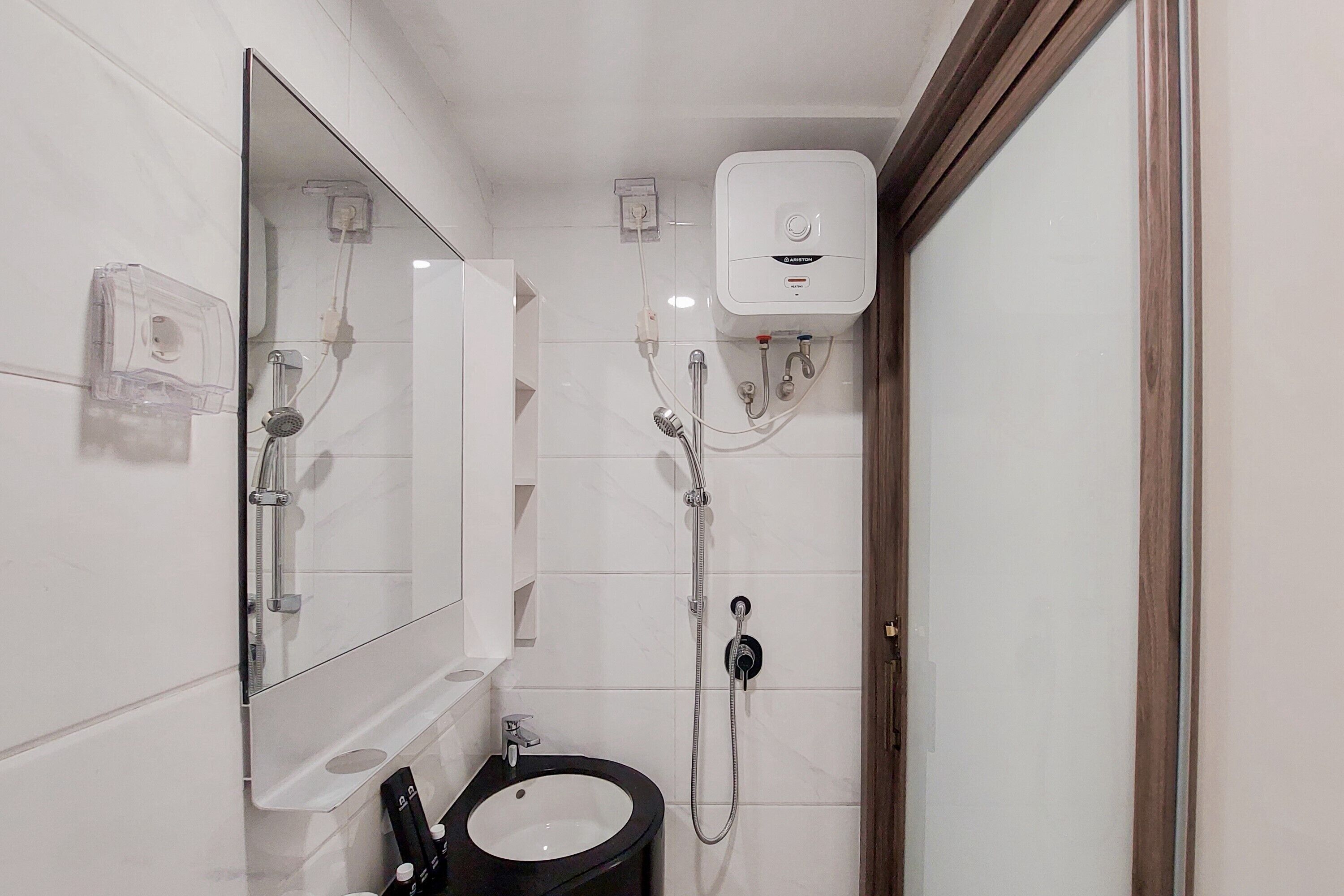 Un bagno piccolo con un lavandino bianco, uno specchio e una doccia con soffione flessibile.