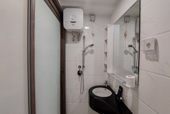 A bathroom with a toilet, sink, mirror, and shower.