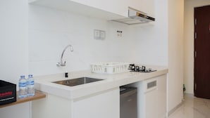 A modern kitchen with white cabinetry, a stainless steel sink, and a dishwasher. - Nice And Comfort Studio Room At Sky House Bsd Apartment (Pagedangan)