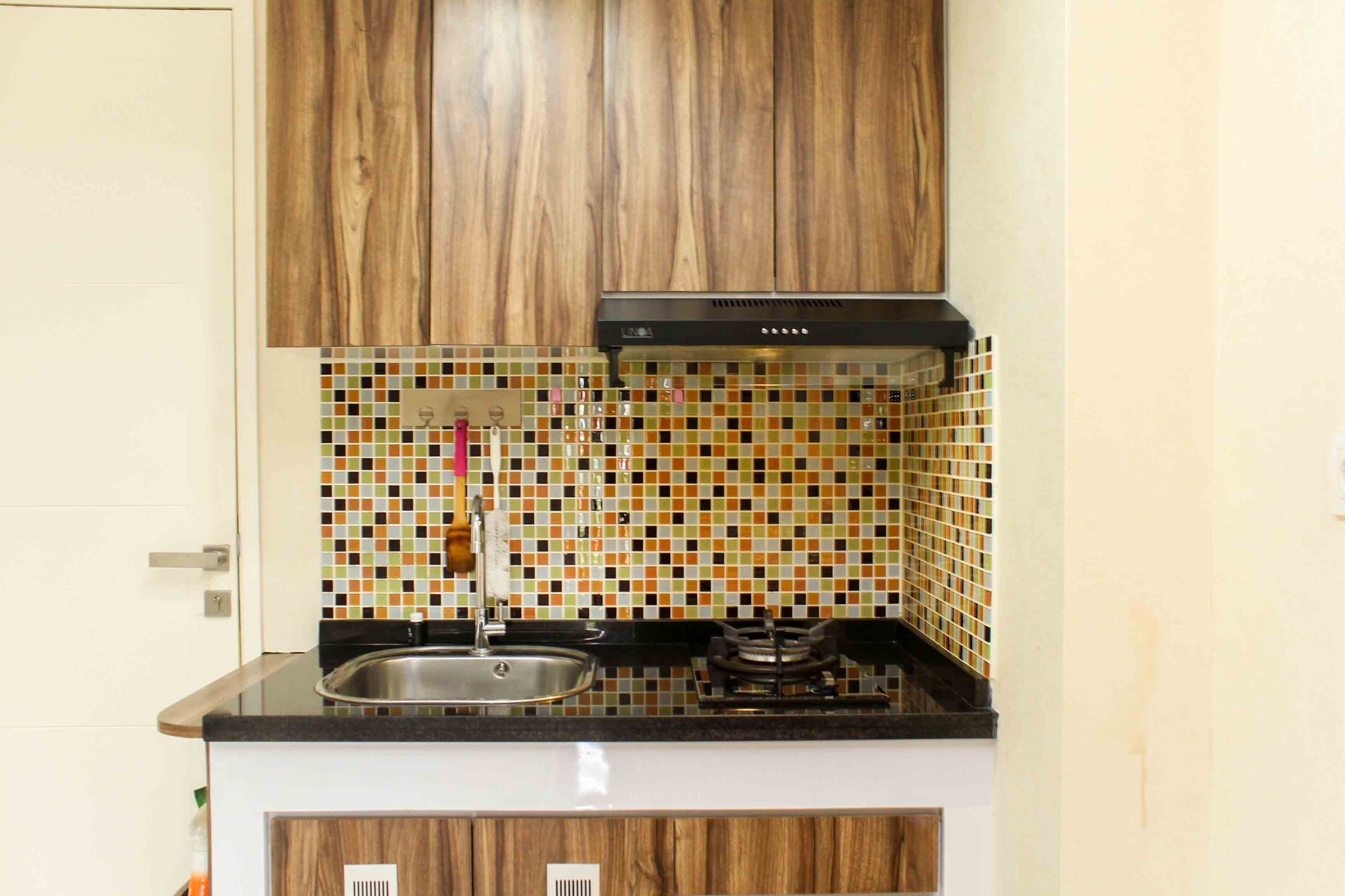 A kitchen with wooden cabinets, a tiled backsplash, a stainless steel sink, and a gas stove.