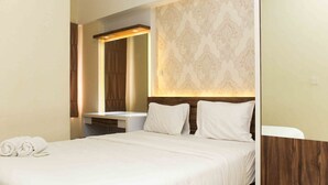 A hotel room with a neatly made bed, a wooden headboard, and a wall-mounted mirror. - Spacious And Nice 2Br At Springlake Summarecon Bekasi Apartment (Bekasi)