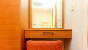 A wooden cabinet with a mirror above a drawer, a towel hanging on a hook, and a light switch on the wall. - Cozy Stay Studio Apartment (No Kitchen) At Metropark Condominium Jababeka (Cikarang)