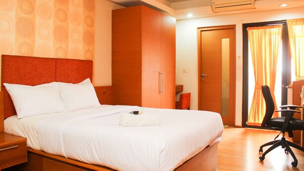 A hotel room with a large bed, a wardrobe, a desk with a chair, and a window with curtains. - Cozy Stay Studio Apartment (No Kitchen) At Metropark Condominium Jababeka (Cikarang)