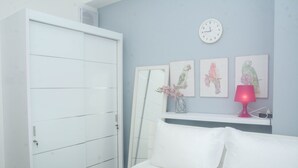 A bedroom with a bed, a wardrobe, a clock, and three bird-themed paintings on the wall. - Modern And Comfort 2Br Apartment At Signature Park Grande (Jakarta)
