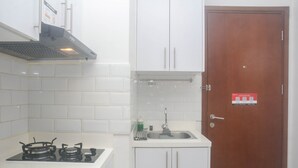 A kitchen with white cabinets, a stainless steel sink, and a gas stove. - Modern And Comfort 2Br Apartment At Signature Park Grande (Jakarta)