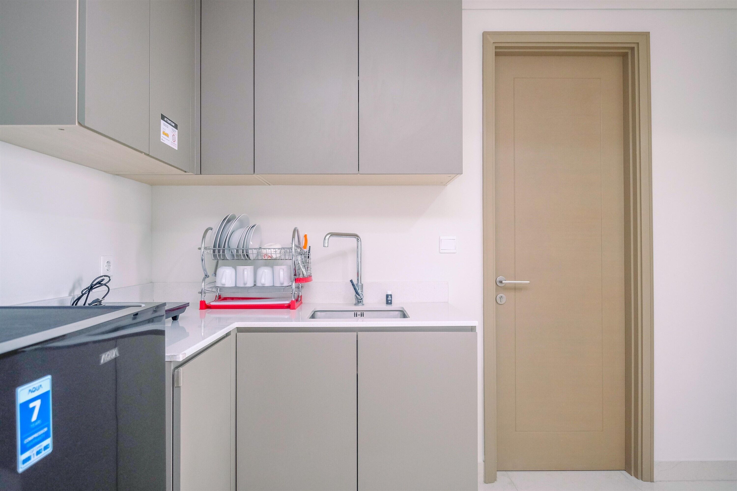 A compact kitchen with grey cabinets, a sink, and a dishwasher.