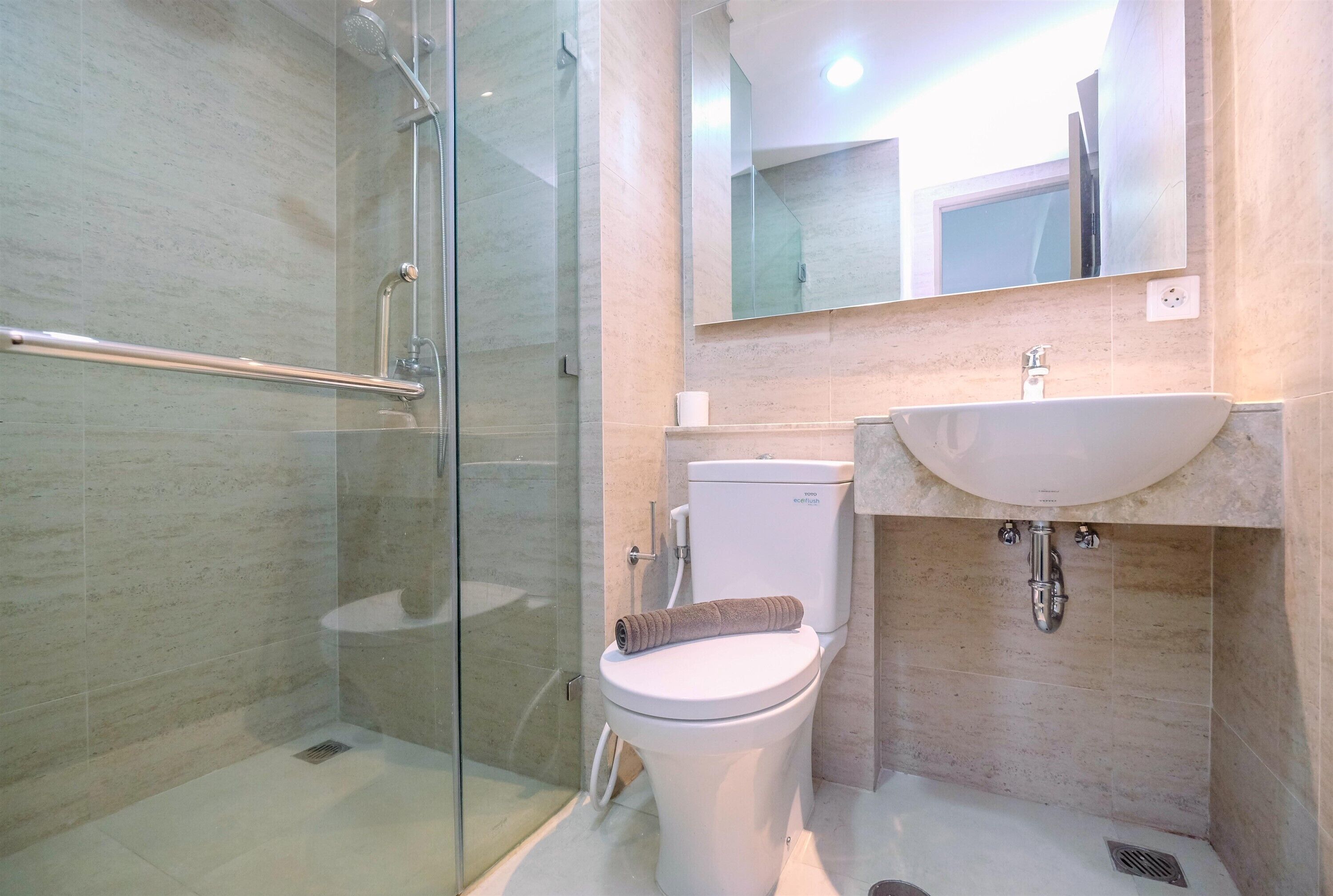 A modern bathroom with a glass shower enclosure, a white toilet, and a sink with a mirror above.