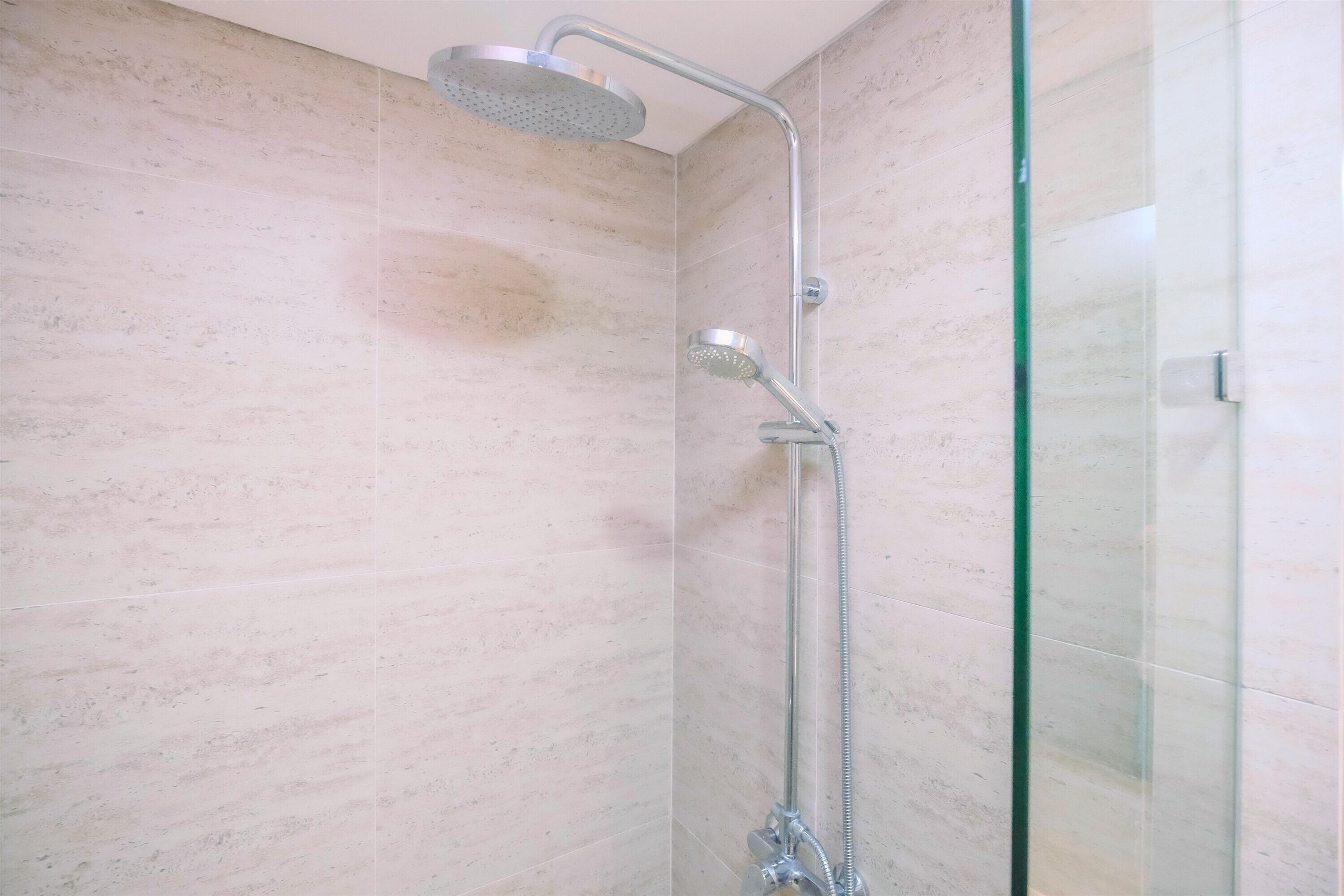 A shower with a handheld showerhead and a fixed overhead showerhead in a tiled room.