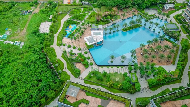 An aerial view of a resort with a large swimming pool, palm trees, and well-maintained gardens. - Comfortable And Minimalist 2Br At Gold Coast Apartment (Jakarta)