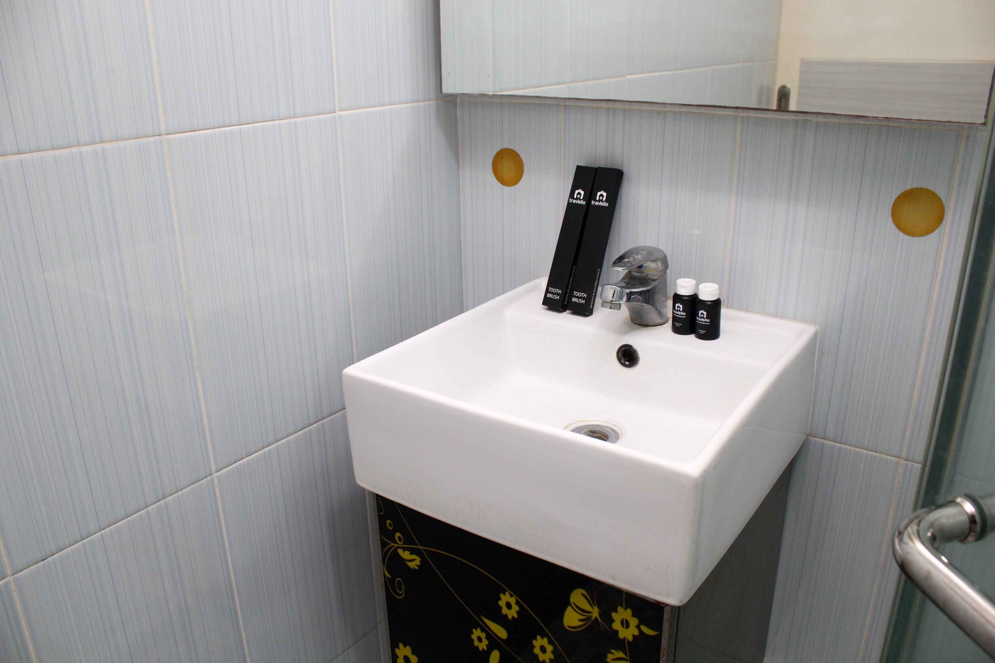 A bathroom sink with a mirror above it, a towel rack, and toiletries on the sink.