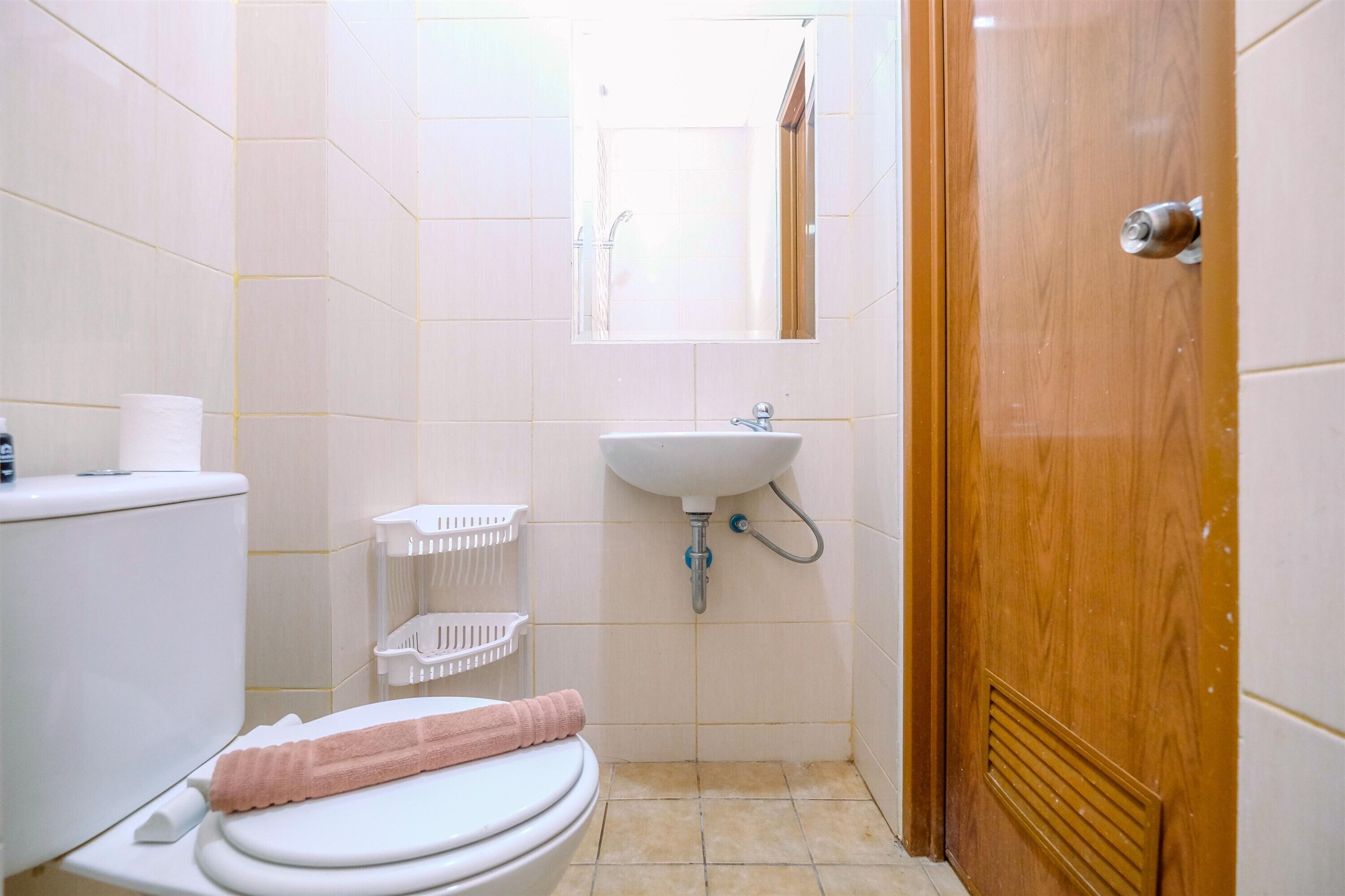 A small bathroom with a toilet, sink, and a wooden door.