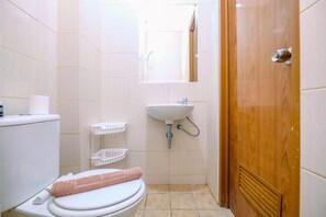 A small bathroom with a toilet, sink, and a wooden door. - Comfortable And Cozy Living Studio Room Apartment At Dave (Depok)
