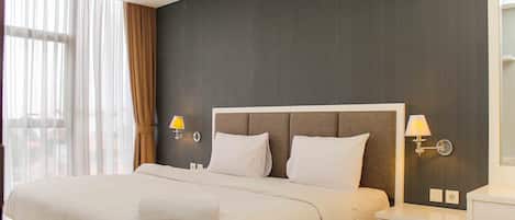Une chambre d’hôtel avec un grand lit, deux lampes de chevet, une table de chevet et une vue sur l’extérieur.