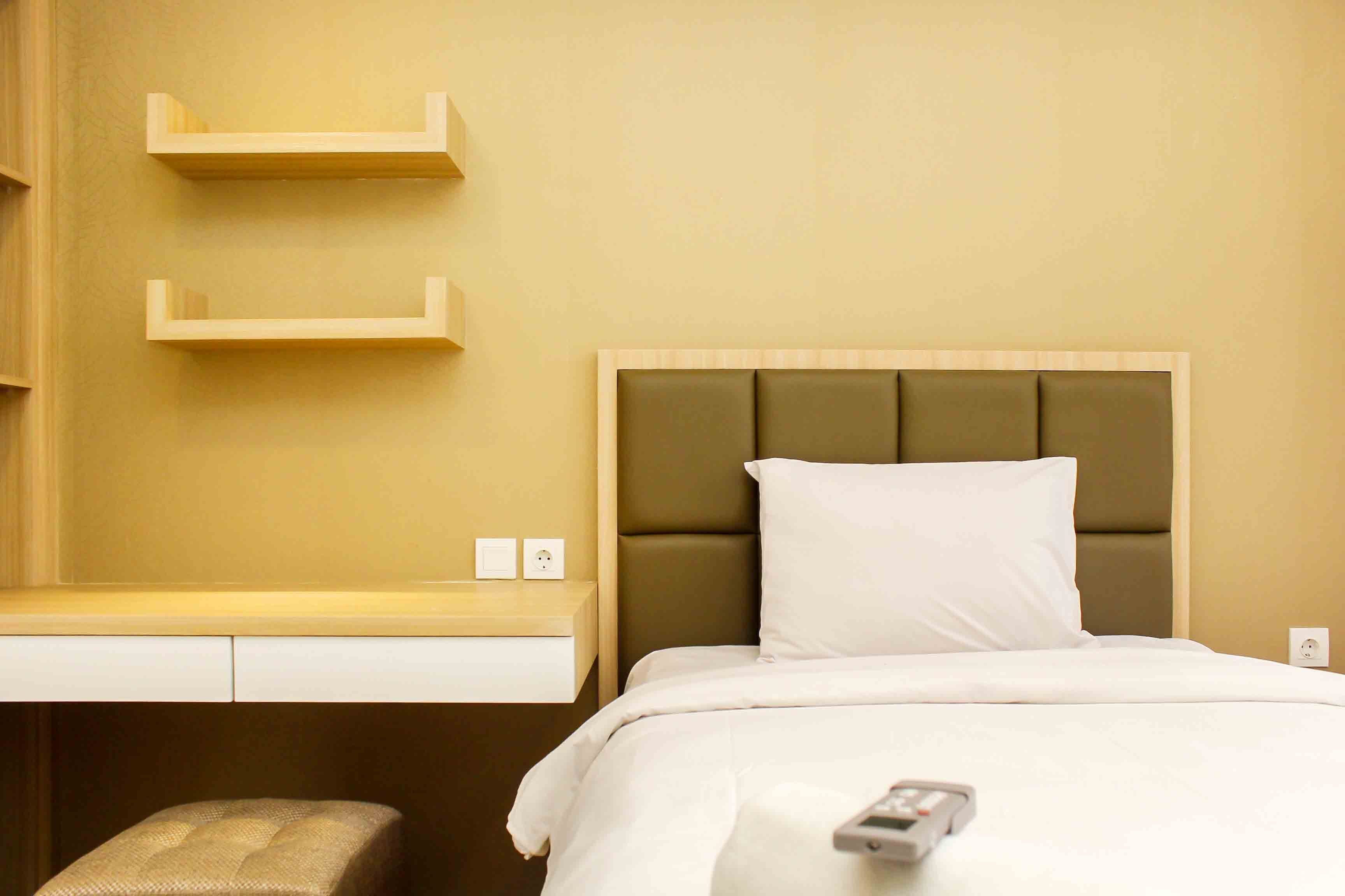 Ein Hotelzimmer mit einem Bett, einem kleinen Schreibtisch und zwei Wandregalen.