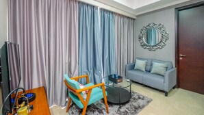 A living room with a sofa, a coffee table, a TV, and curtains.