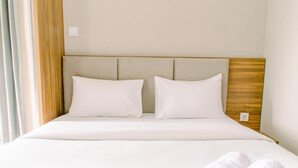 A hotel room with a bed, two pillows, a wooden headboard, and a window with curtains. - Comfy Studio At Amazana Serpong Apartment (South Tangerang)