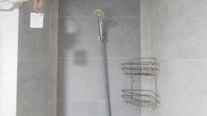 A shower area with a handheld showerhead, a wall-mounted faucet, and two metal towel racks. - Cozy Stay Studio Apartment At Taman Melati Surabaya (Surabaya)