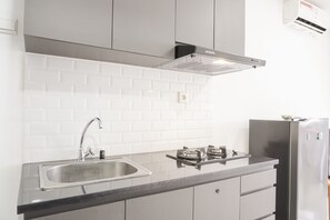 A modern kitchen with a stainless steel sink, a gas stove, and a built-in oven. - Stunning Studio Apartment At Belmont Residence Puri (Jakarta)