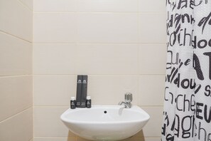 A bathroom with a white sink, a faucet, and a shower curtain with black text. - Stunning Studio Apartment At Belmont Residence Puri (Jakarta)