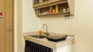 A compact kitchen with a sink, a cabinet above it, and a door to the left. - Comfort And Serene 2Br At Meikarta Apartment (Cikarang)