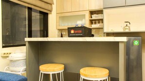 A compact kitchenette with two wooden stools, a travelio branded food and beverage cooler, and a stainless steel refrigerator. - Comfortable And Spacious 2Br At Meikarta Apartment (Cikarang)