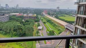 A high-rise building with a view of a cityscape, including roads, greenery, and other buildings. - Pleasurable Studio At Sky House Bsd Apartment (Pagedangan)