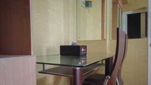 Una habitación pequeña con una mesa de vidrio, una caja negra sobre la mesa y una silla marrón.