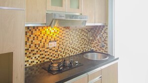 Una cocina con armarios de madera, salpicadero de azulejos, un lavamanos de acero inoxidable y una estufa a gas.