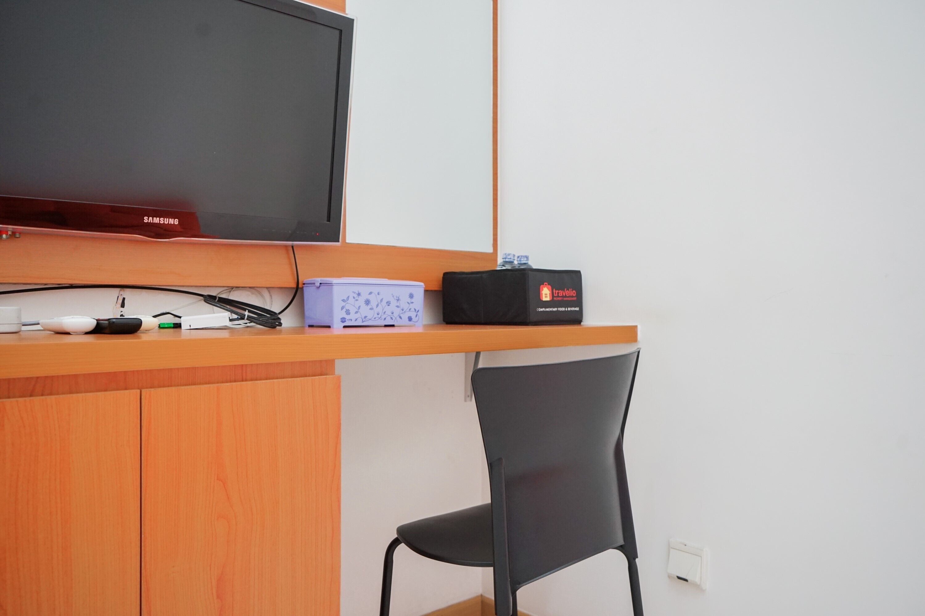 A small workspace with a Samsung TV, a travel radio, and a chair.