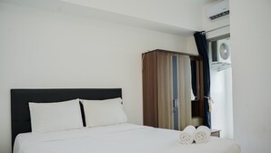 A hotel room with a bed, a wardrobe, and an air conditioning unit. - Restful And Cozy 2Br Apartment At M-Town Residence (Gading Serpong)
