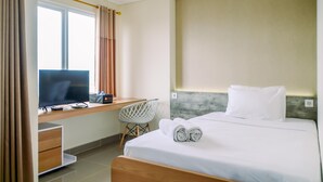 Une chambre d’hôtel avec un lit, un bureau avec un ordinateur, une chaise et une fenêtre avec des rideaux.
