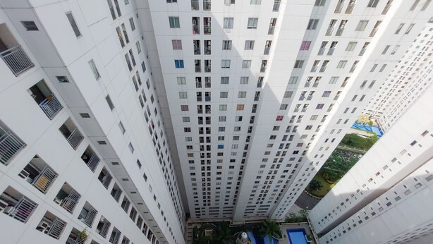 A high-rise residential building with multiple balconies and a rooftop pool area. - Comfort 2Br Apartment At Bassura City (Jakarta)