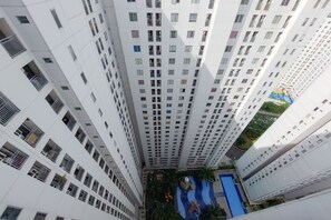 A high-rise residential building with multiple balconies and a rooftop pool area. - Comfort 2Br Apartment At Bassura City (Jakarta)