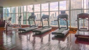 A gym with treadmills and exercise equipment, large windows with a city view, and a wooden floor. - New Furnished And Comfortable 2Br At The Mayflower Apartment (Jakarta)