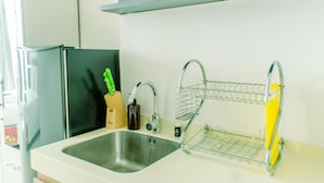 A kitchen with a stainless steel sink, a black refrigerator, and a yellow kitchen cart. - Nice And Cozy Studio At Tree Park City Apartment (Tangerang)