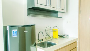 A modern kitchen with a stainless steel refrigerator, a sink, and a yellow dish rack. - Nice And Cozy Studio At Tree Park City Apartment (Tangerang)