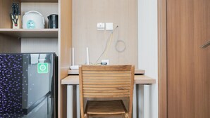 A compact kitchen with a wooden chair, a countertop, and a refrigerator. - Minimalist And Comfort 1Br At B Residence (Pagedangan)