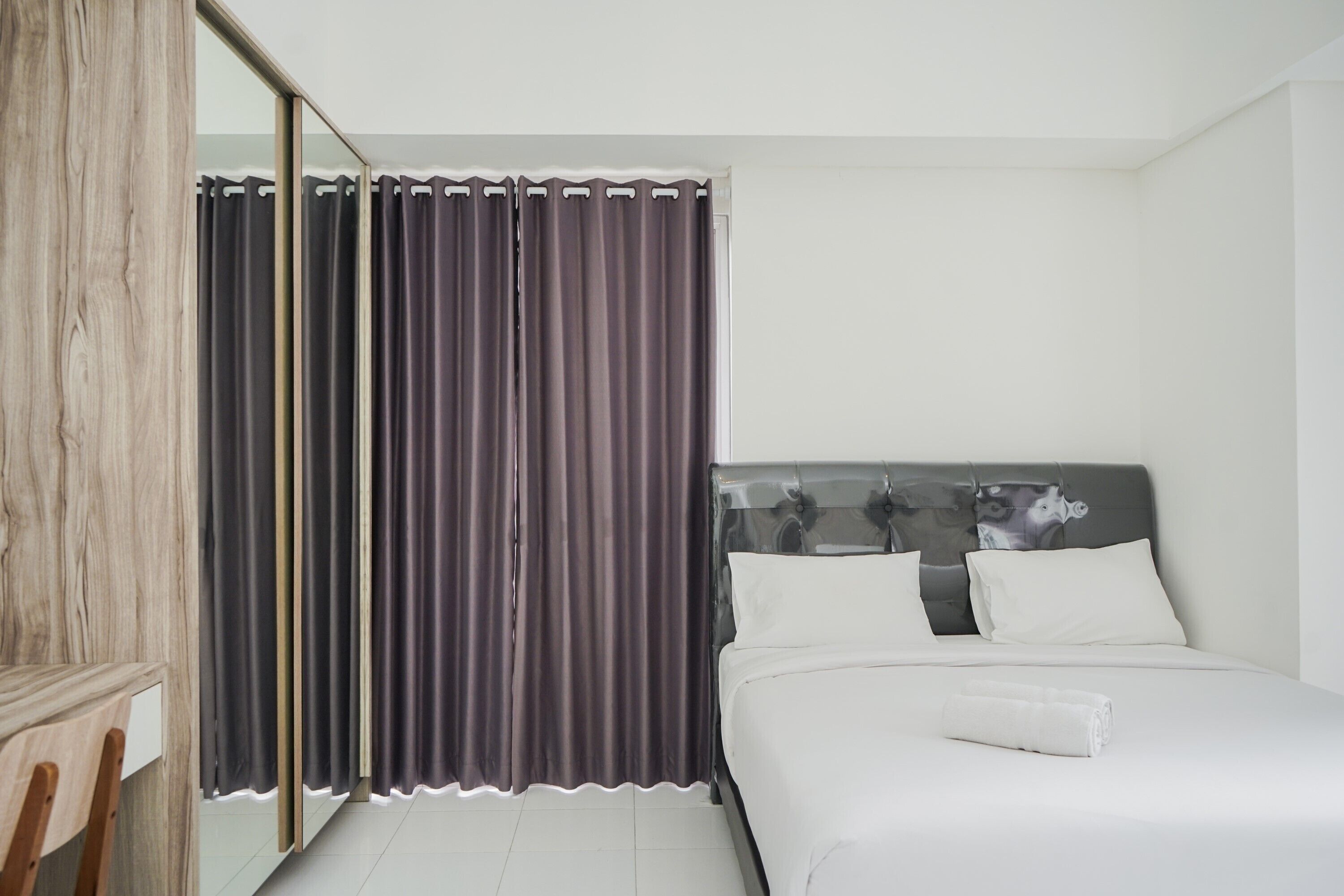 A modern bedroom with a bed, a wooden chair, and a mirror.