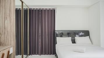 A modern bedroom with a bed, a wooden chair, and a mirror.