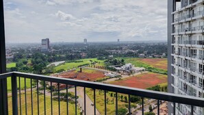 Un edificio de gran altura con múltiples balcones, vistas a un paisaje urbano con varios edificios y un parque verde en primer plano.