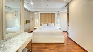 A modern hotel room with a large bed, a marble bedside table, and a large mirror.