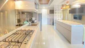 A modern kitchen with stainless steel appliances, a central island, and a view into the dining area.
