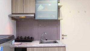 A compact kitchen with a built-in stove, a sink, and wooden cabinets. - Spacious And Good 2Br At Springlake Summarecon Bekasi Apartment (Bekasi)
