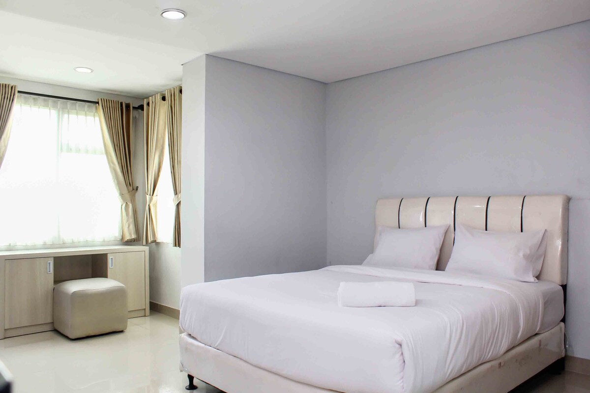 A modern bedroom with a large bed, a built-in desk, and a window with curtains.