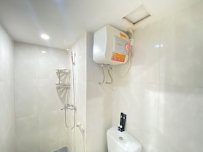 A bathroom with a shower, a toilet, and a water heater.