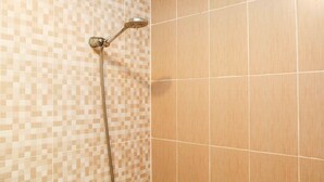 A shower with a checkered tile wall and a plain tiled wall.