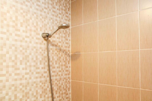 Una ducha con pared de azulejos a cuadros y otra pared de azulejos lisos.