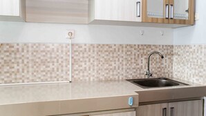A kitchen with a tiled backsplash, a stainless steel sink, and wooden cabinets.