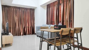 A modern hotel room with a dining area, a sofa, and curtains. - Big And Comfy 3Br At Vida View Apartement (Makassar)