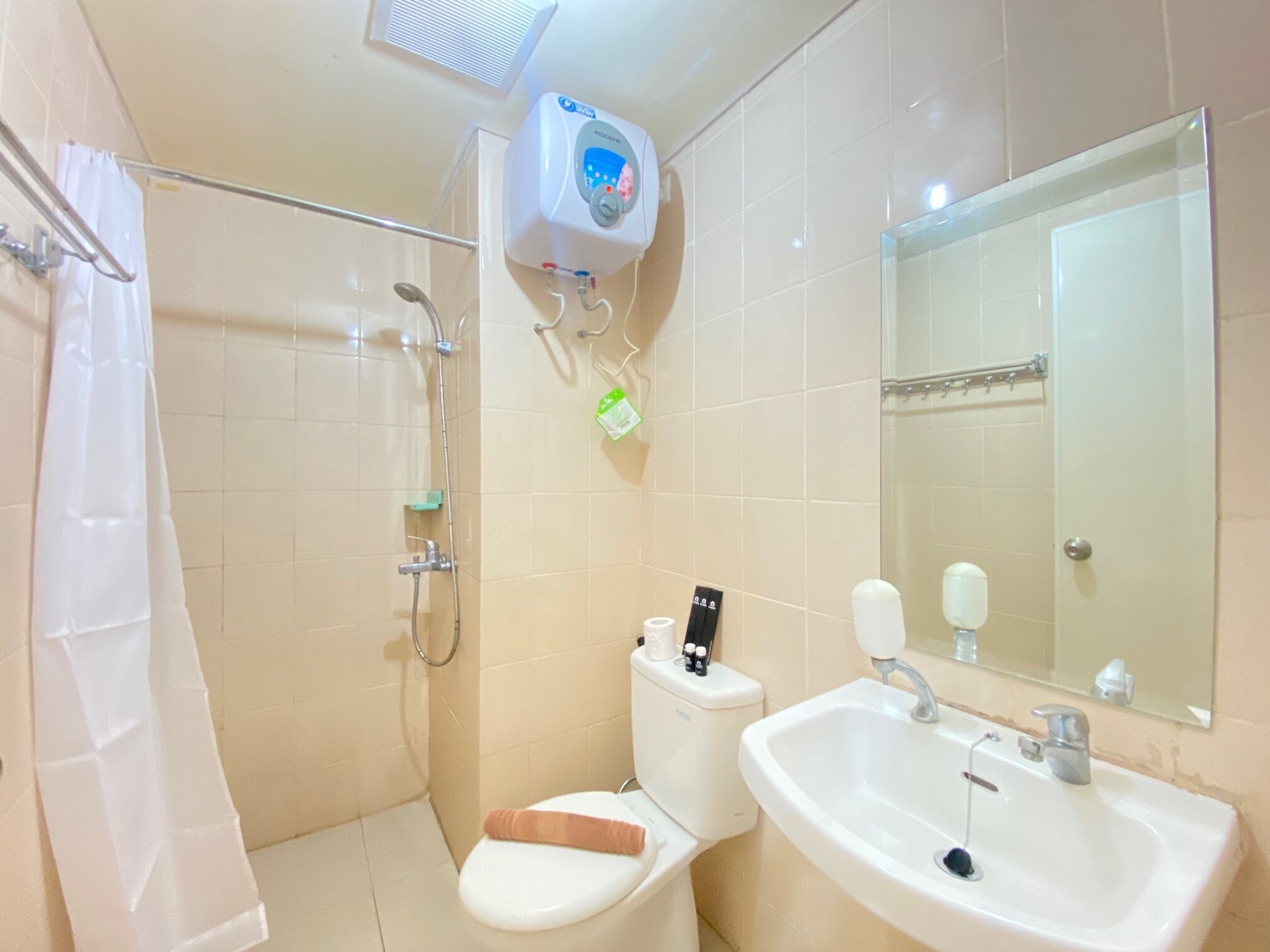 Ein Badezimmer mit Dusche, Toilette, Waschbecken und Spiegel.